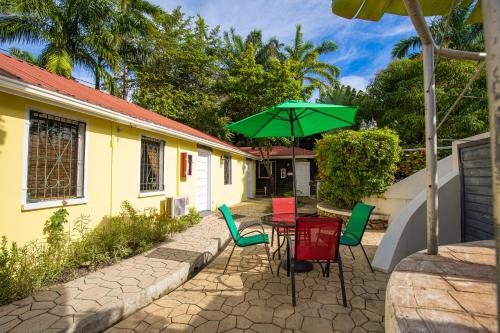 a table and chairs with a green umbrella at Harbour View Boutique Hotel & Wellness Retreat in Belize City