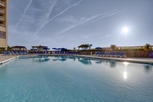 uma grande piscina com cadeiras azuis num resort em Holiday Inn Resort Lumina on Wrightsville Beach, an IHG Hotel em Wrightsville Beach