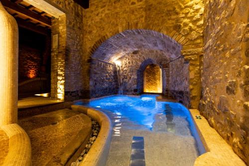 an indoor swimming pool in a building with a stone wall at Oste del Castello Wellness & Bike Hotel in Verucchio