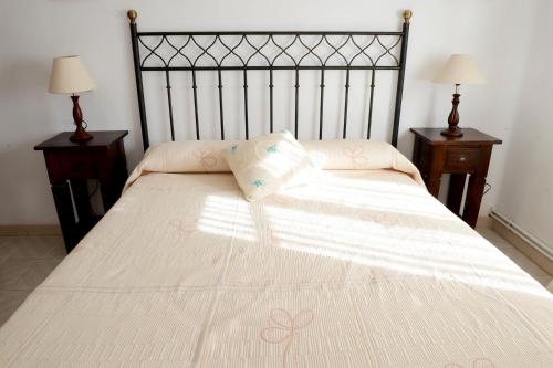 a bed with a white comforter and two night stands at Hostal-Restaurante Fogón de Gredos in Guisando