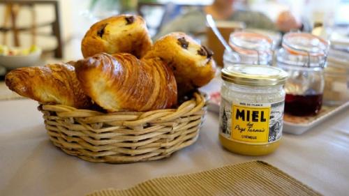 - un panier de viennoiseries sur une table avec un pot de miel dans l'établissement Le lodge de La Boissière, à Andillac