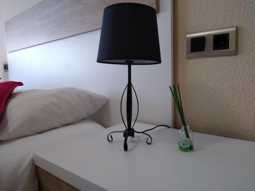 a black lamp sitting on a table next to a bed at Apartamentos La Rosa - Calamocha in Calamocha