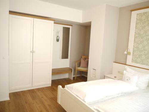 a white bedroom with two beds and a closet at Hotel Ratsstuben in Lindau