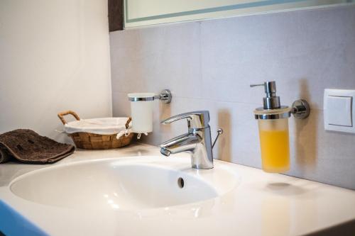 - un lavabo avec un robinet et un verre de jus d'orange dans l'établissement Apartment CANUS - Krumas Living - Kronplatz, à San Lorenzo di Sebato