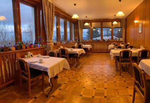 um restaurante com mesas e cadeiras brancas e janelas em Pensjonat Paradise em Karpacz