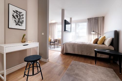 a bedroom with a bed and a desk and stool at SAXX Apartments Leipzig in Leipzig