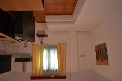 a kitchen with a window with yellow curtains at Skyros Panorama Studios in Skiros