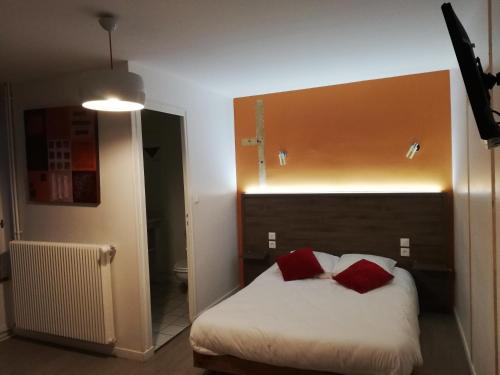 a bedroom with a bed with two red pillows at La Poularde in Louhans