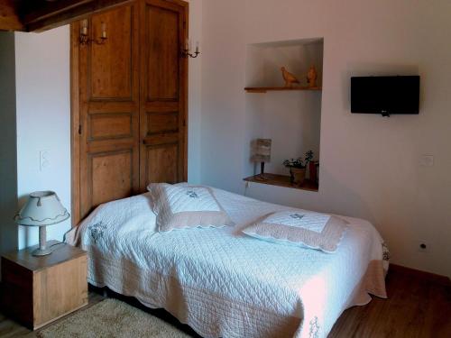 a bedroom with a bed with a wooden door and a television at Les Terrasses de Saillans in Saillans