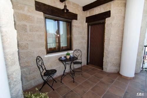 a patio with two chairs and a table and a window at Casa Rural La Molinera Riolobos Caceres in Ríolobos