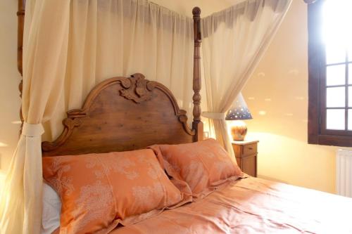 a bedroom with a wooden canopy bed with orange pillows at MAISON DE NOSTRADAMUS*** OCCITANIE INSOLITE in Alet-les-Bains