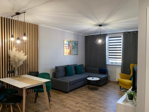 uma sala de estar com um sofá e uma mesa em ApartamentLeśna12Hel em Hel