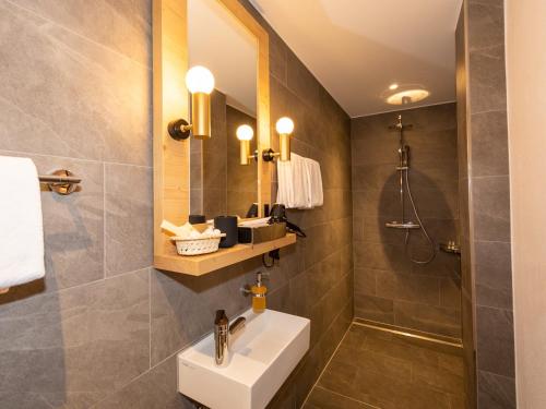 a bathroom with a shower, sink, and mirror at Hotel Parsenn in Davos