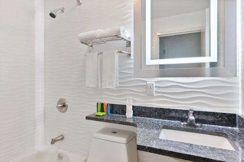 een badkamer met een wastafel, een toilet en een spiegel bij Casa Blanca Hotel Brooklyn in Brooklyn