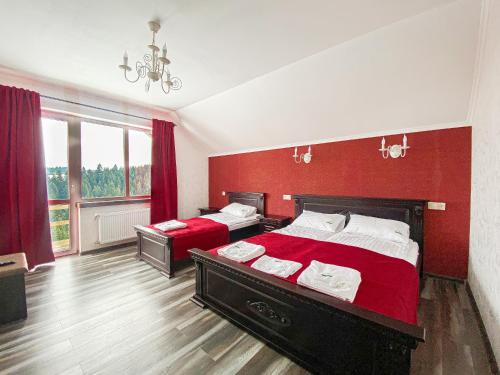 a bedroom with two beds and a red wall at Мелодія Гір Вид на гори in Vorokhta