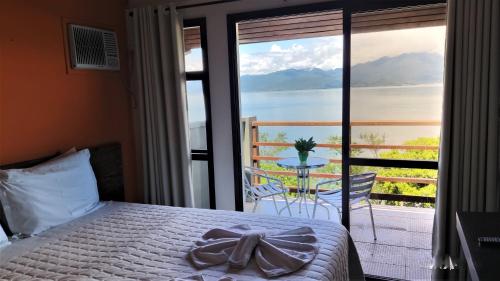 a bedroom with a bed and a view of the ocean at Pousada Ecomar in Florianópolis