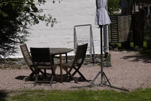 a table and two chairs and an umbrella at Petite maison Normande in Bellou-en-Houlme