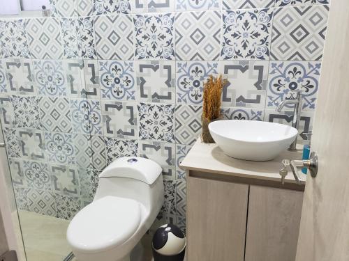 a bathroom with a white toilet and a sink at Piscina & Descanso - Puerto Azul- con todas las comodidades! in Ricaurte