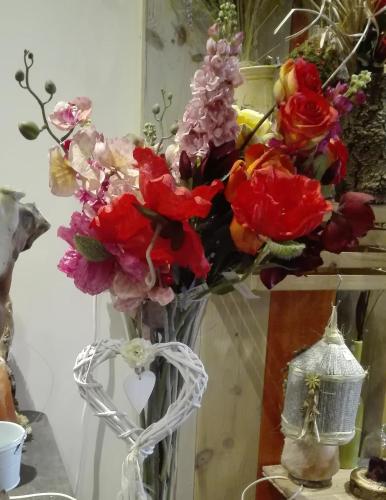 a vase filled with red and pink flowers on a table at Les Terrasses de Saillans in Saillans
