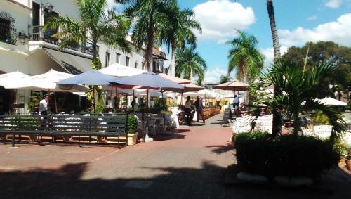 een patio met parasols, tafels en stoelen bij Hotel Aluge in Santo Domingo