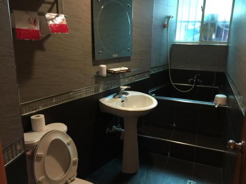 a bathroom with a toilet and a sink and a mirror at Riyuexing Hotel in Taipei