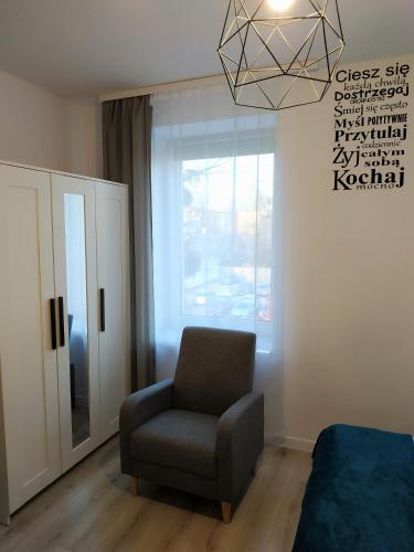 a living room with a chair and a window at theApartments Manufaktura in Łódź
