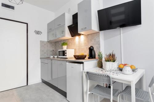 a white kitchen with a table and a microwave at theApartments Manufaktura in Łódź