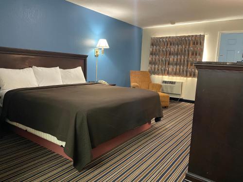 Habitación de hotel con cama y silla en Budget Inn Motel, en Bourbon