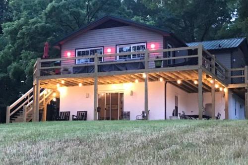 a large house with a deck with lights on it at Belmont NC Riverfront 2-Bedroom Garden Suite in Charlotte