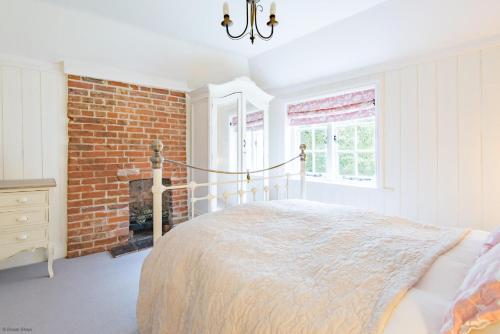 a bedroom with a bed and a brick wall at Oast Barn Cottage by Bloom Stays in Faversham