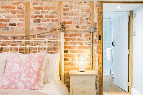 - une chambre avec un lit et un mur en briques dans l'établissement Oast Barn Cottage by Bloom Stays, à Faversham