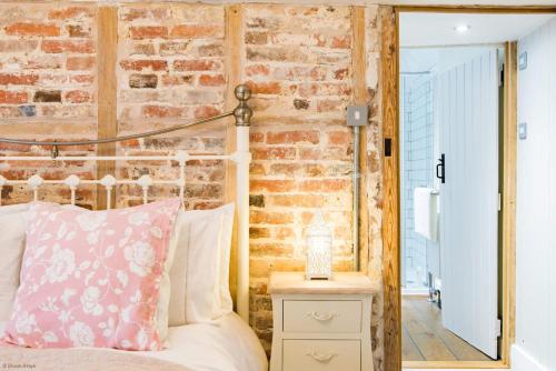 ein Schlafzimmer mit einem Bett und einer Ziegelwand in der Unterkunft Oast Barn Cottage by Bloom Stays in Faversham