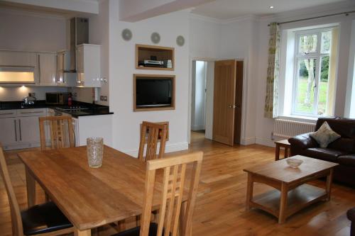 cocina y sala de estar con mesa de madera y sillas en Shanklin Manor en Shanklin