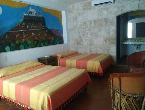 a room with two beds and a painting on the wall at Casa Maru Hotel in Parras de la Fuente