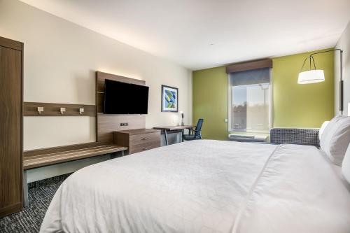 a hotel room with a bed and a flat screen tv at Holiday Inn Express & Suites Tulsa East - Catoosa by IHG in Catoosa
