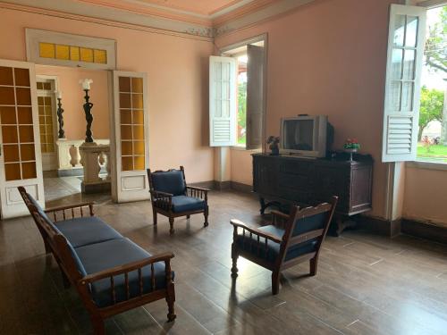 a living room with chairs and a tv and a table at Hotel Valenciano in Valença