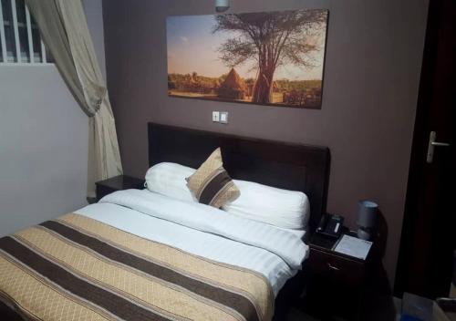 a bed in a bedroom with a picture on the wall at BENIN CITY CENTER HOTEL in Cotonou