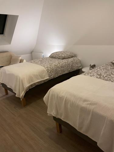 two beds in a room with white walls at L épicéa in Mélamare