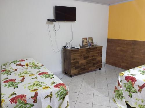a room with two beds and a tv on a wall at Pouso do Beija-Flor in Cavalcante