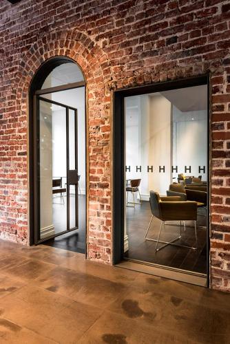 a room with a brick wall with a glass door at Hougoumont Hotel Fremantle in Fremantle