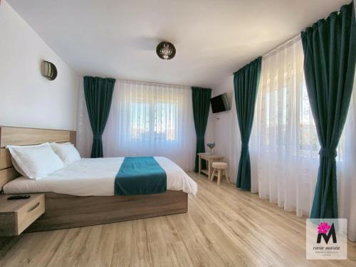 a bedroom with a large bed with green curtains at CasaMarta in Baile Felix