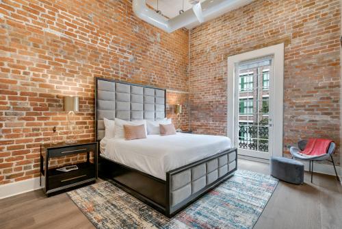 a bedroom with a bed and a brick wall at The St John in New Orleans