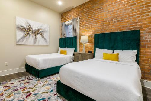 deux lits dans une chambre avec un mur de briques dans l'établissement The Pontchartrain, à La Nouvelle-Orléans