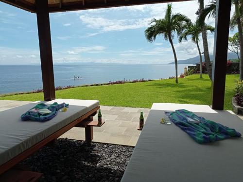 a view of the ocean from a patio with two tables at Absolute Beachfront, Paradise, 3BR Villa with Private Pool on 1200m2 of Tropical Land in Tulamben