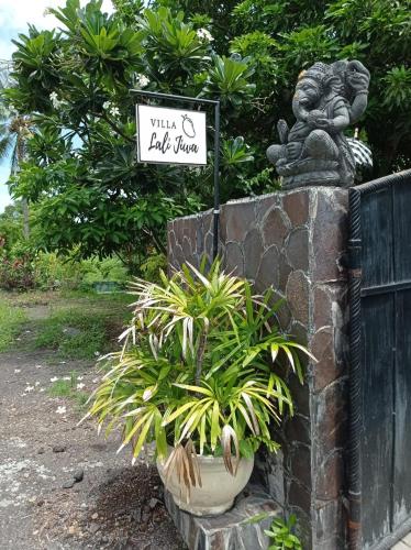 a sign on a stone wall with a plant at Absolute Beachfront, Paradise, 3BR Villa with Private Pool on 1200m2 of Tropical Land in Tulamben