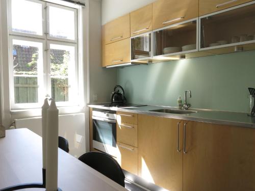 cocina con armarios de madera, fregadero y mesa en ApartmentInCopenhagen Apartment 1141, en Copenhague