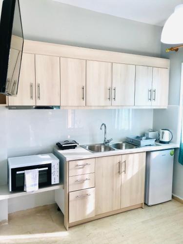 a kitchen with wooden cabinets and a sink and a microwave at Banos Apartment 2 bed rooms And Swimming Pool in Roda