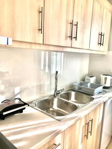a kitchen with a stainless steel sink and wooden cabinets at Banos Apartment 2 bed rooms And Swimming Pool in Roda