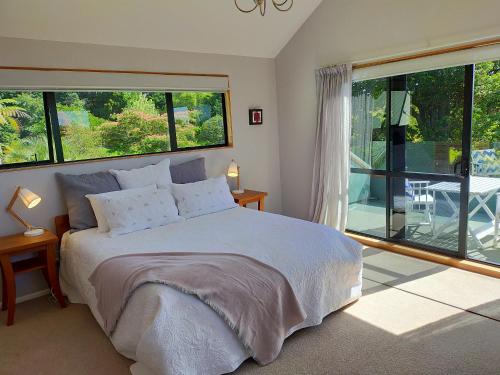 a bedroom with a large bed and large windows at Dangela Boutique Lodge in Auckland