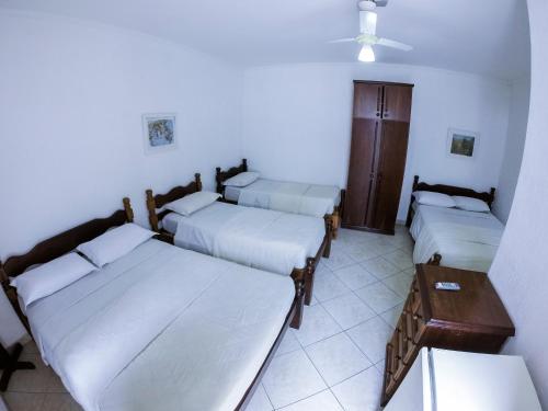 a room with three beds and a table at Hotel Morada do Mar in Guarujá